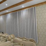 Grey blackout curtains installed across a wide window